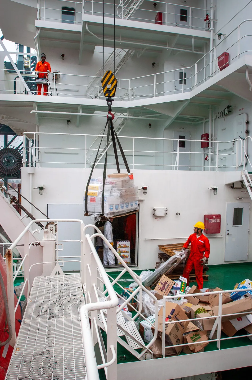 Ship's crane lifting supplies aboard a vessel